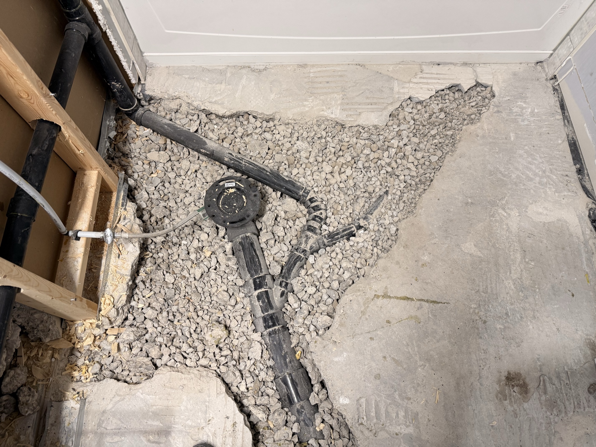 Basement drain rough-in with ABS pipe in gravel bed, ready for inspection