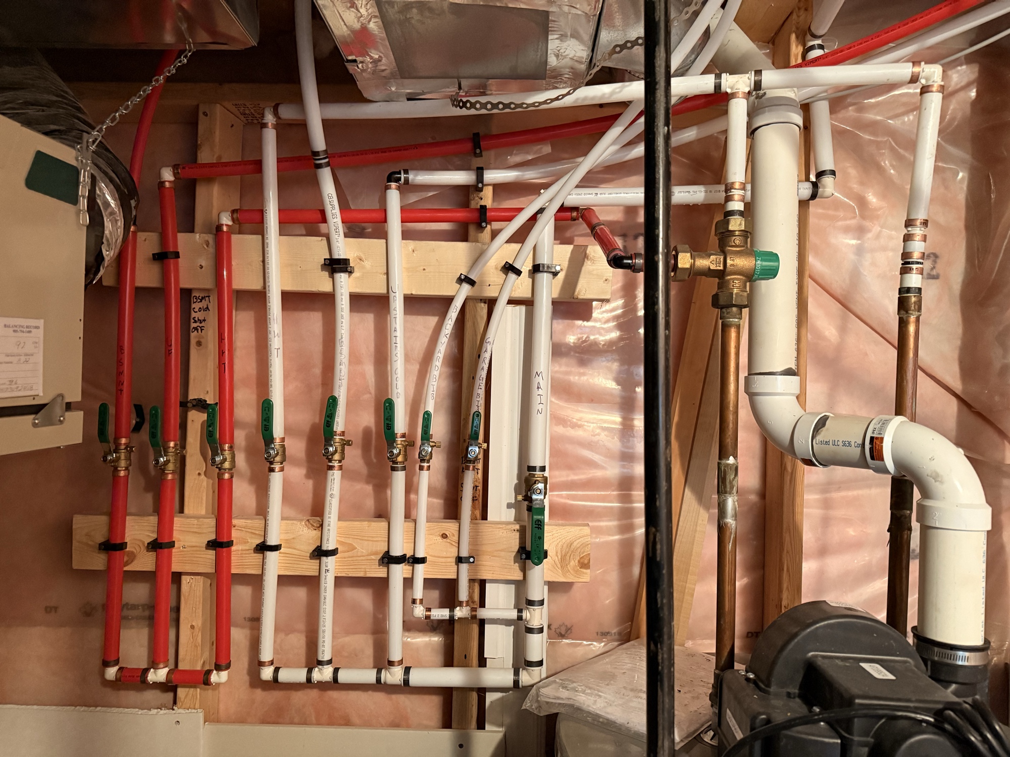 Water supply manifold with labelled PEX lines and individual shutoff valves for basement suite separation